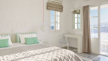 A bedroom with a bed, a desk, and a view of the city.
