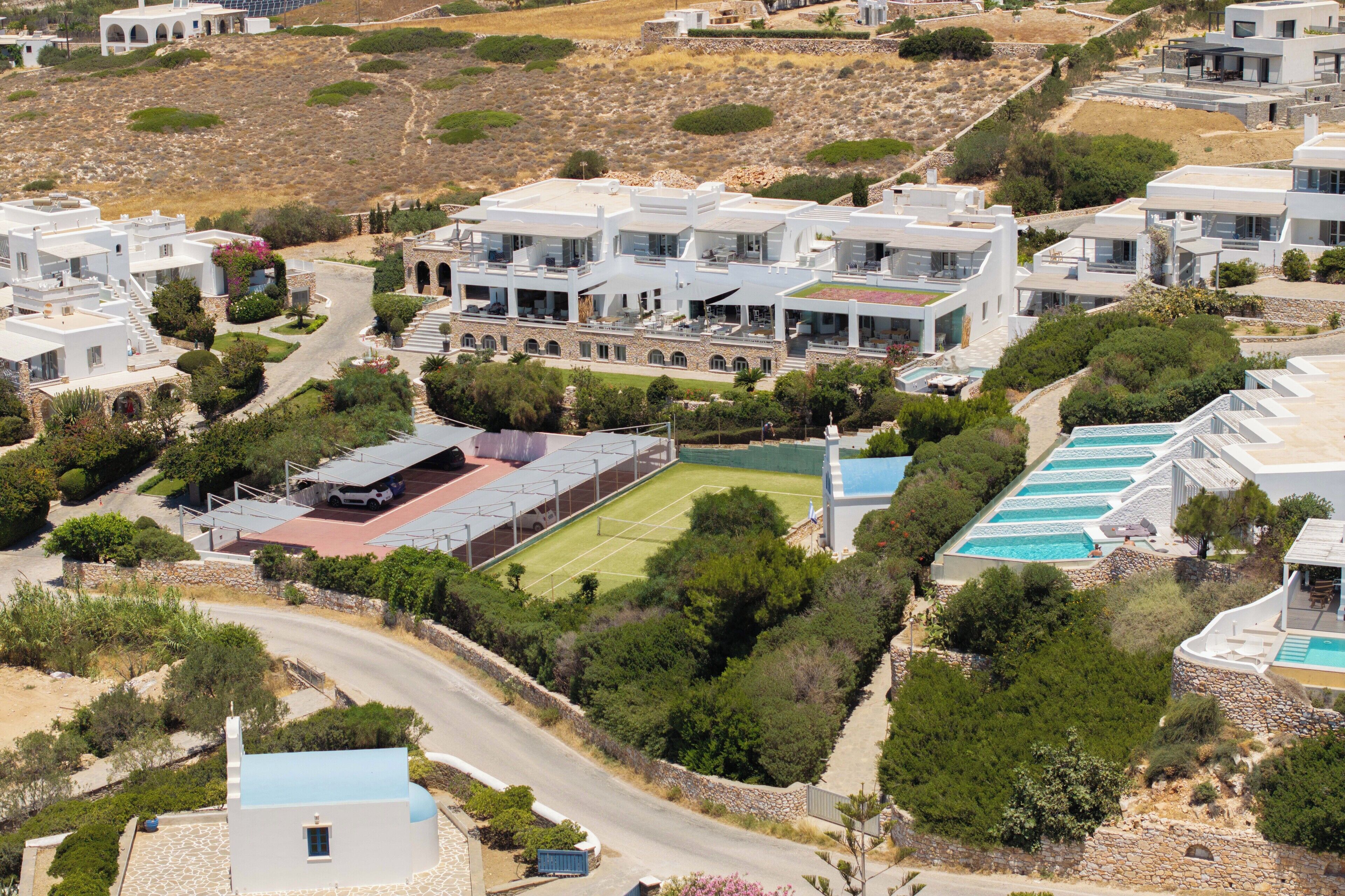 A modern residential area with multiple white buildings, a tennis court, and a swimming pool.