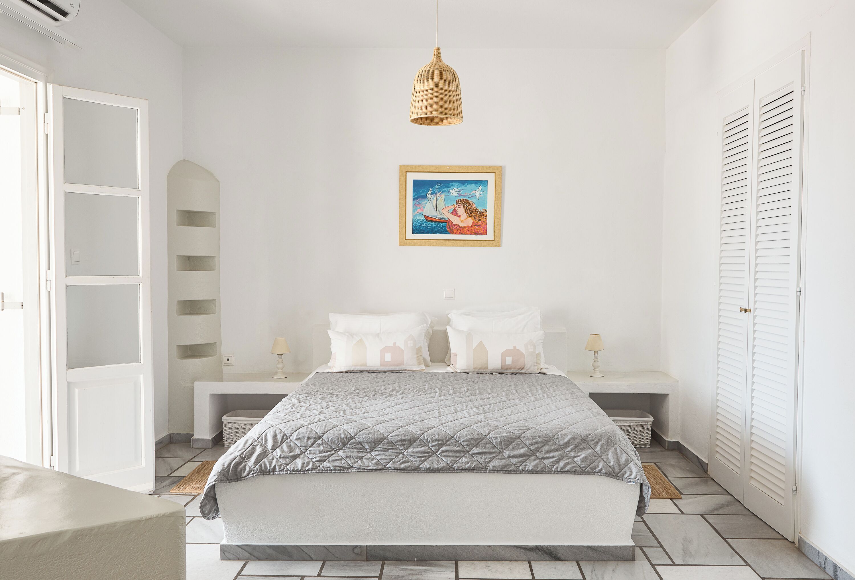 A bedroom with a bed, bedside tables, a hanging light, a framed picture, and a wardrobe.