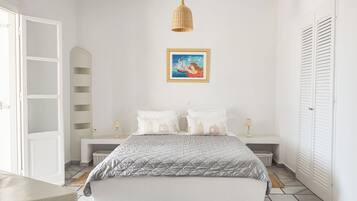 Ein Schlafzimmer mit einem Bett, Nachttischen, einer Hängelampe, einem gerahmten Bild und einem Kleiderschrank.