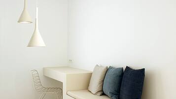A minimalist room with a wooden bench, a white sofa with blue cushions, and two pendant lights.
