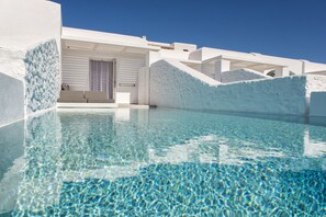 Una piscina cristalina con un moderno edificio blanco al fondo.