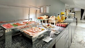 A buffet with various food items including meats, pastries, and fruit. - Hotel Exe Isla Cartuja (Seville)