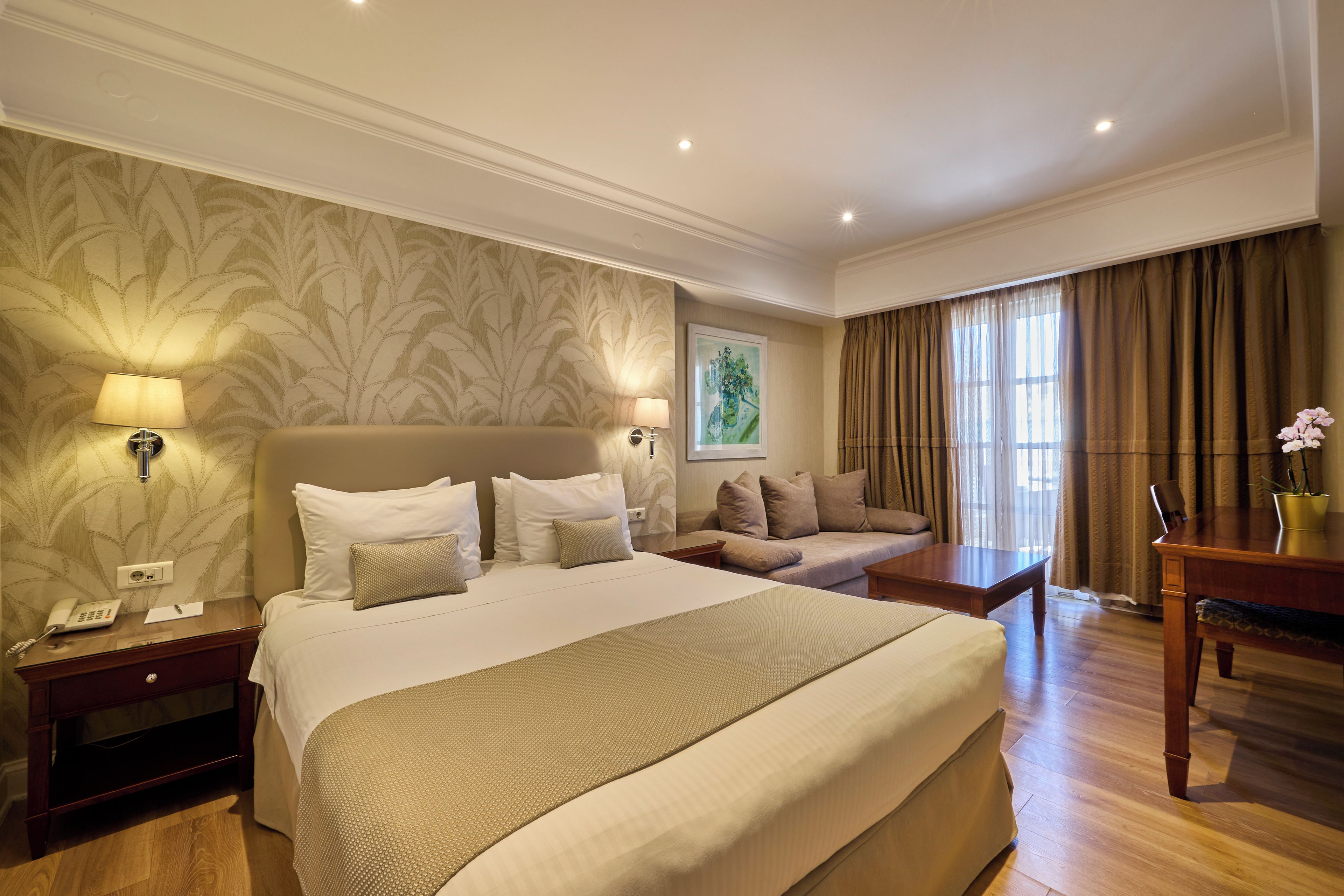 Ein Hotelzimmer mit einem großen Bett, einer Sitzecke, einem Schreibtisch und einem Telefon.