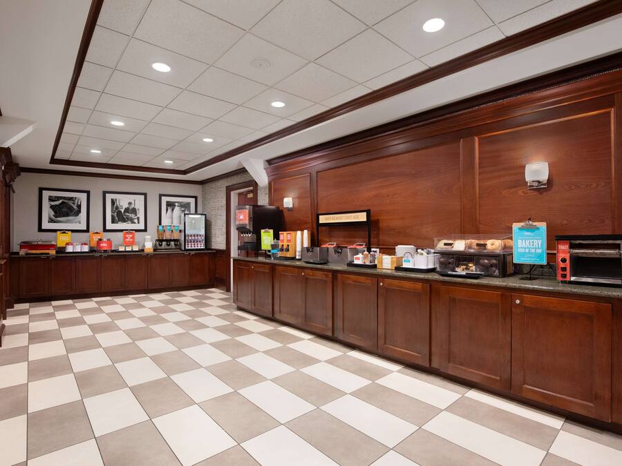 A hotel lobby with a checkered floor, wooden paneling, a bakery counter, and framed pictures on the wall.
