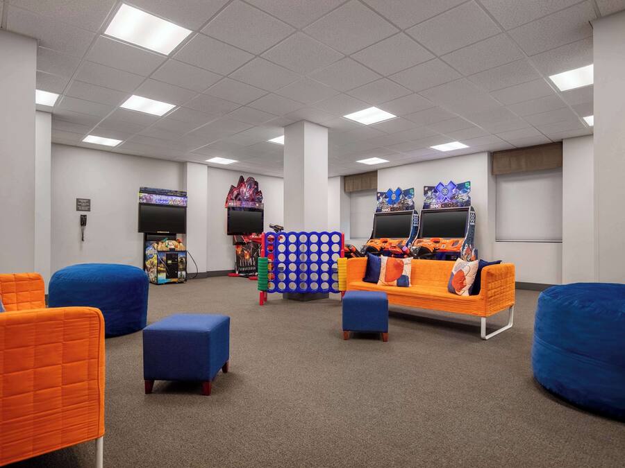 A room with blue and orange seating, a large blue and orange sofa, and a wall-mounted TV.