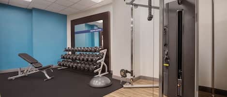 A gym with a bench, dumbbells, and a cable machine.