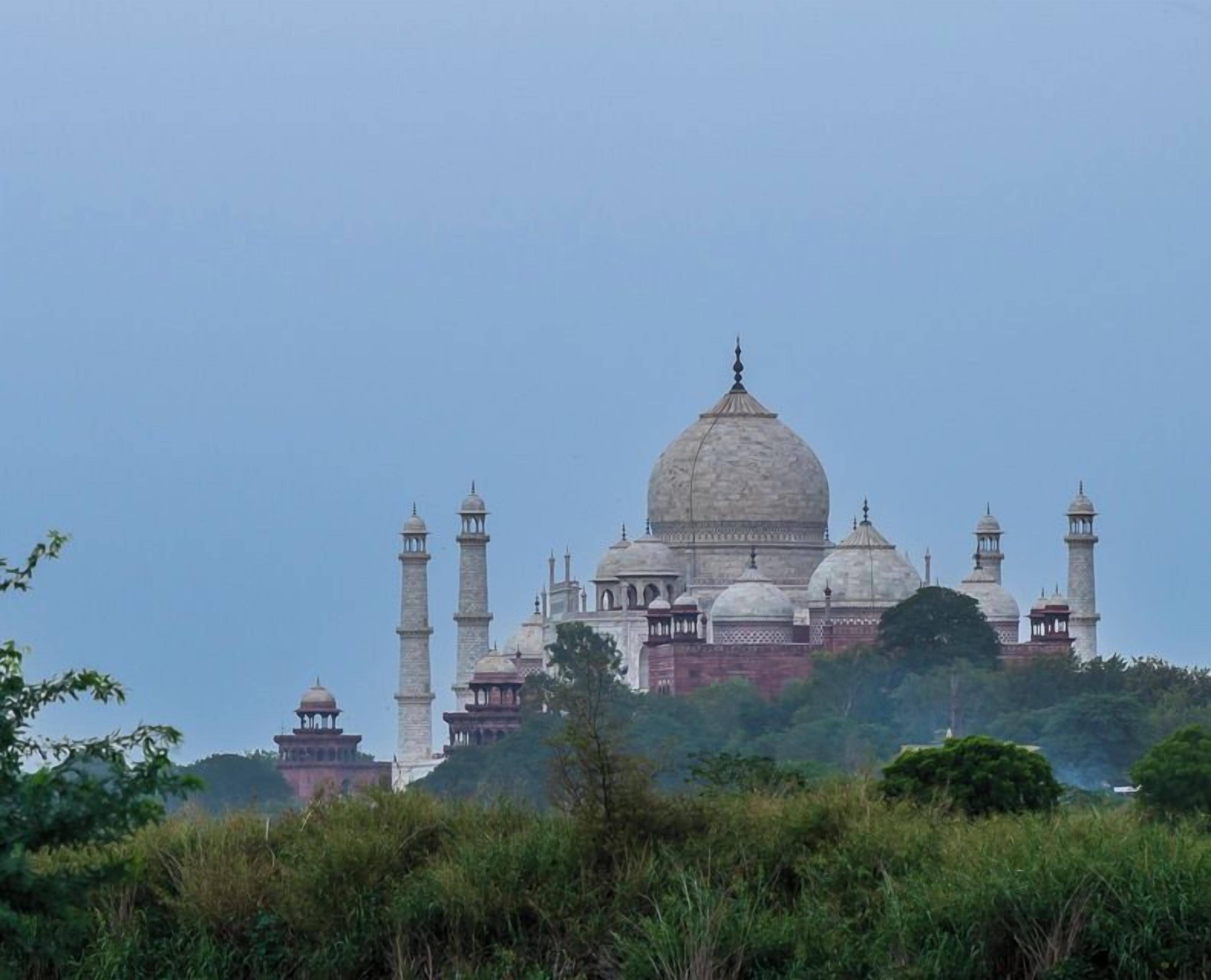 Un grand bâtiment historique doté d’un dôme central et de quatre minarets, entouré de verdure.