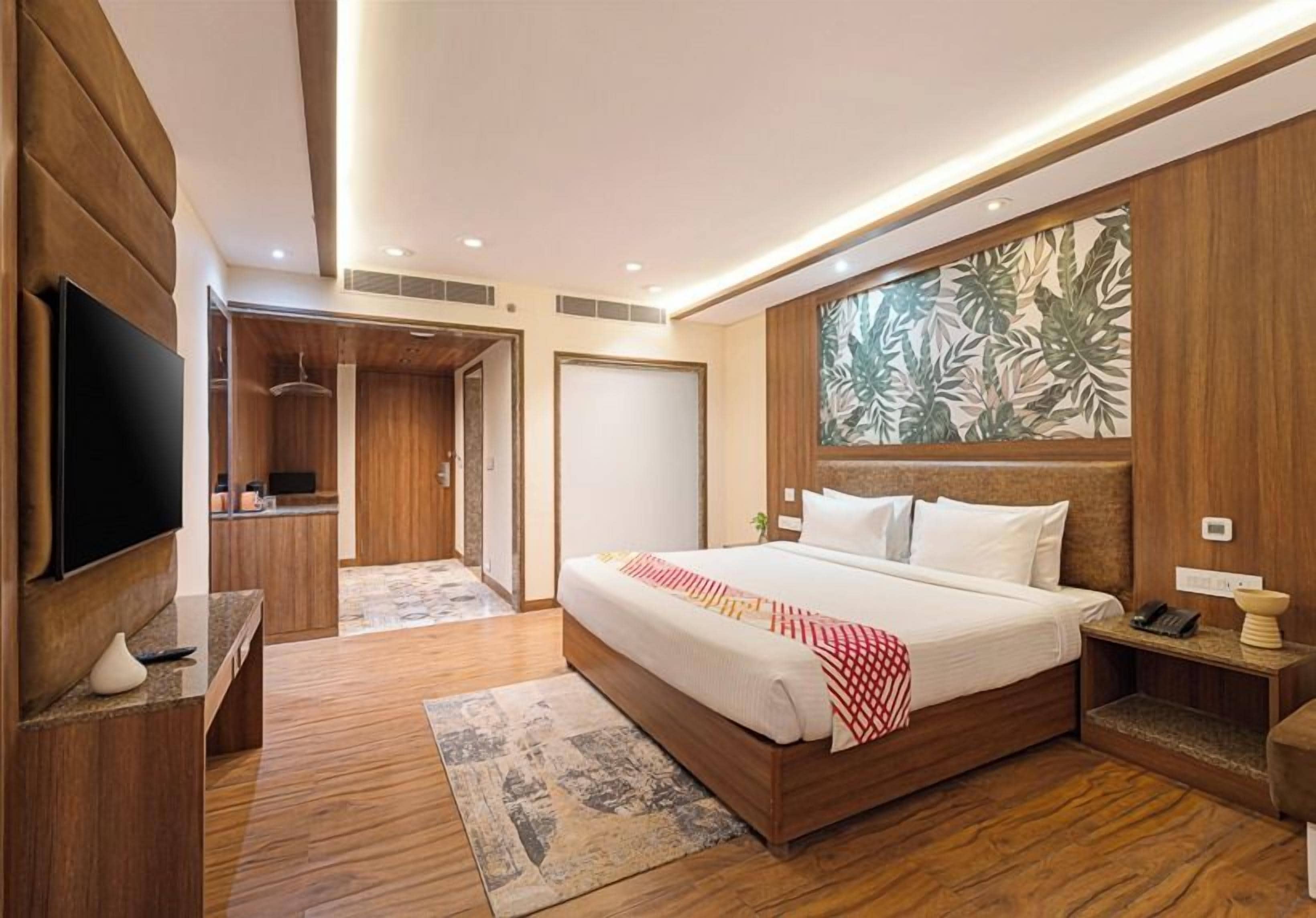 Una habitación de hotel moderna con una cama grande, televisión, escritorio y baño con paneles de madera.