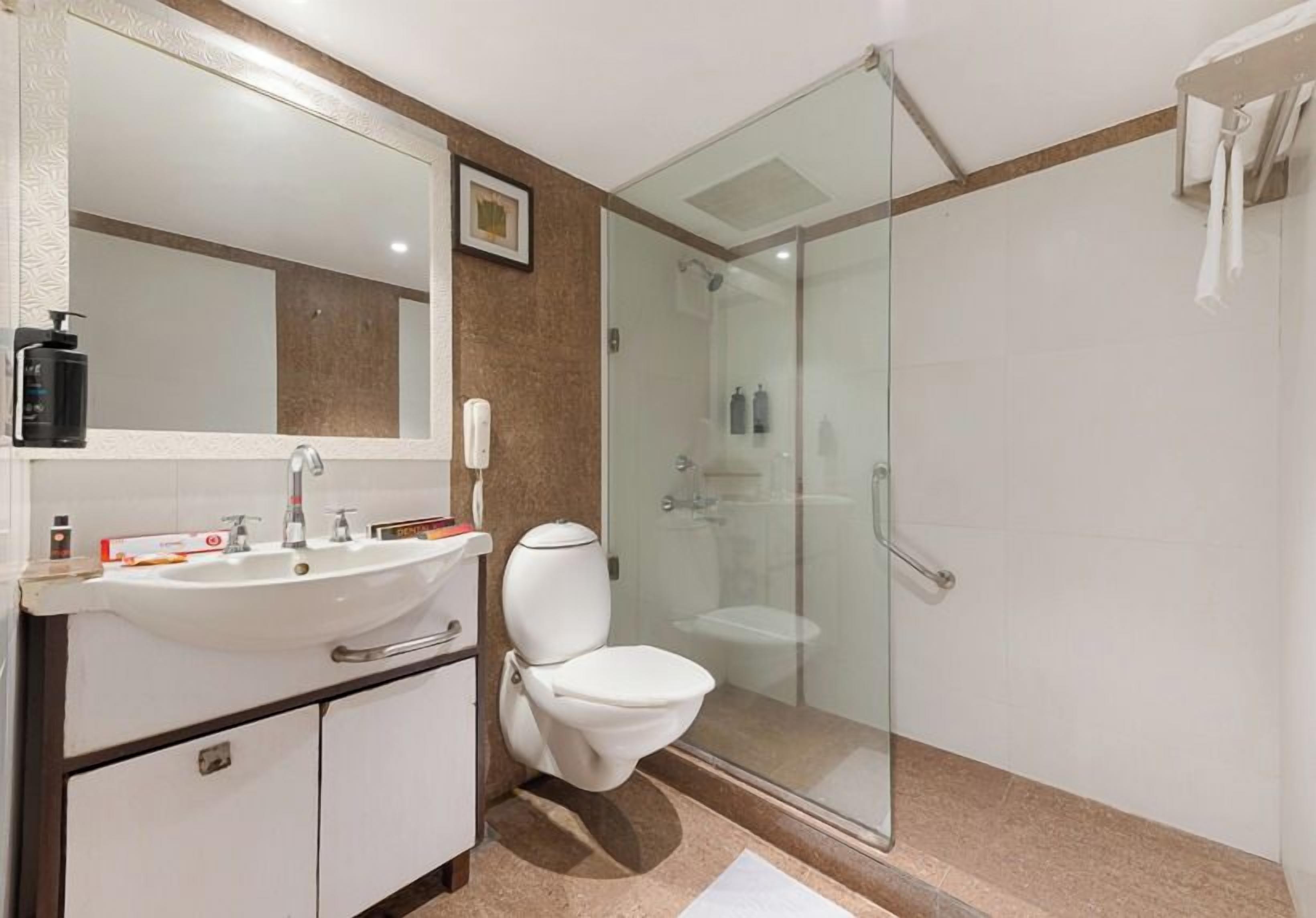 A bathroom with a glass-enclosed shower, a white sink, and a toilet.