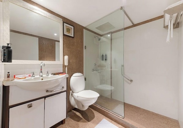 A bathroom with a glass-enclosed shower, a white sink, and a toilet. - Ginger Agra, Fatehabad Road (Agra)