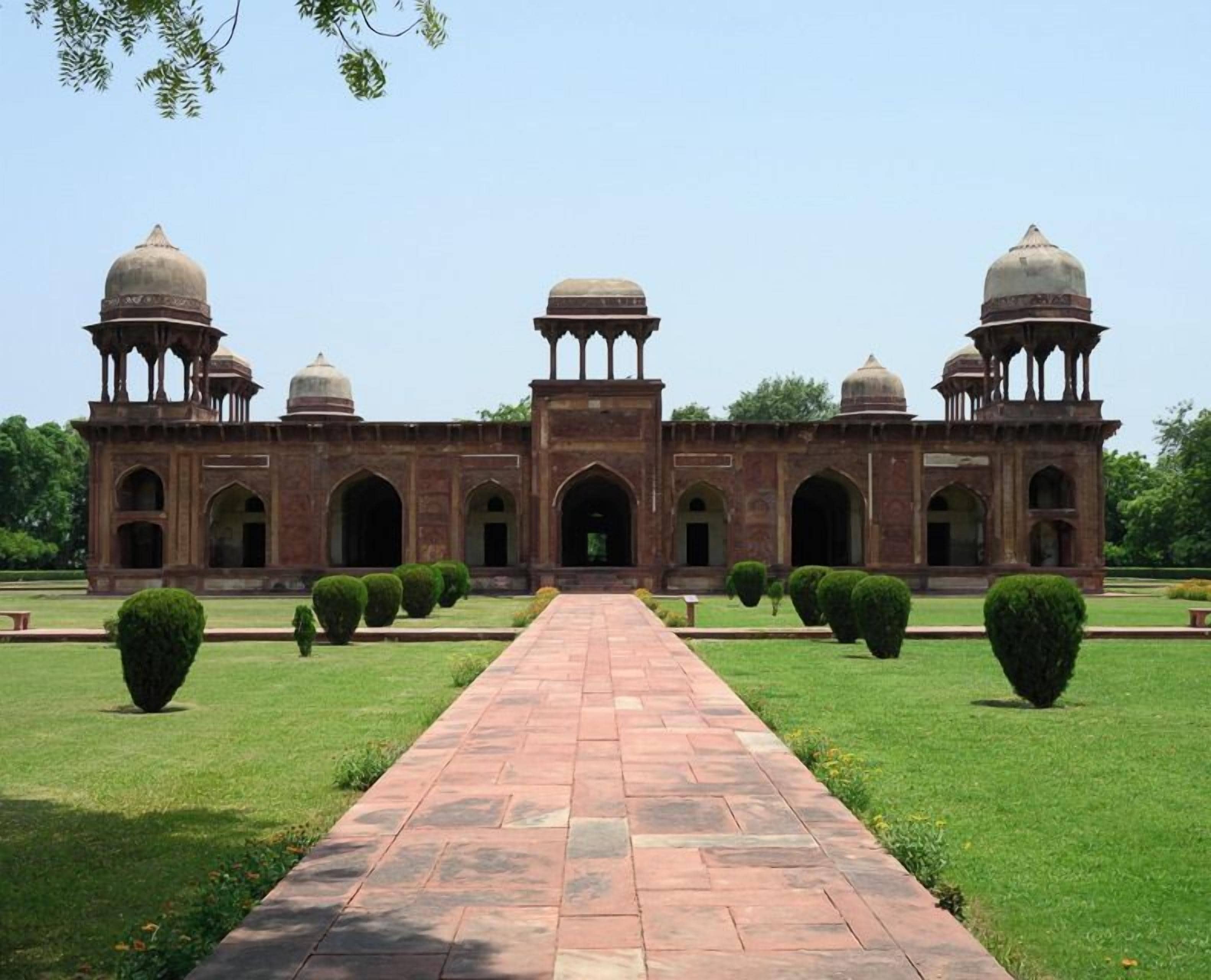 A historical building with a central archway, symmetrical wings, and domed structures.
