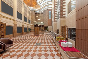 Eine geräumige Lobby mit Schachbrettmuster-Boden, einer Rezeption und einer langen Buffettheke.