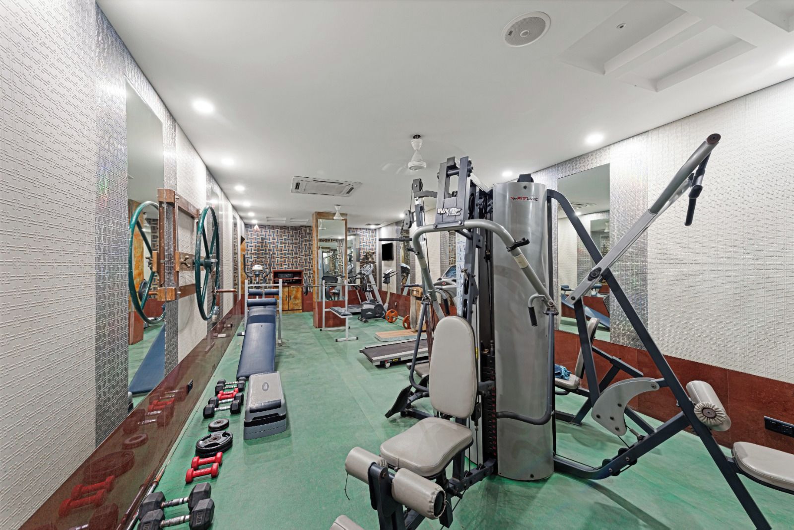 A gym with various exercise equipment, including a treadmill, weight machines, and free weights.