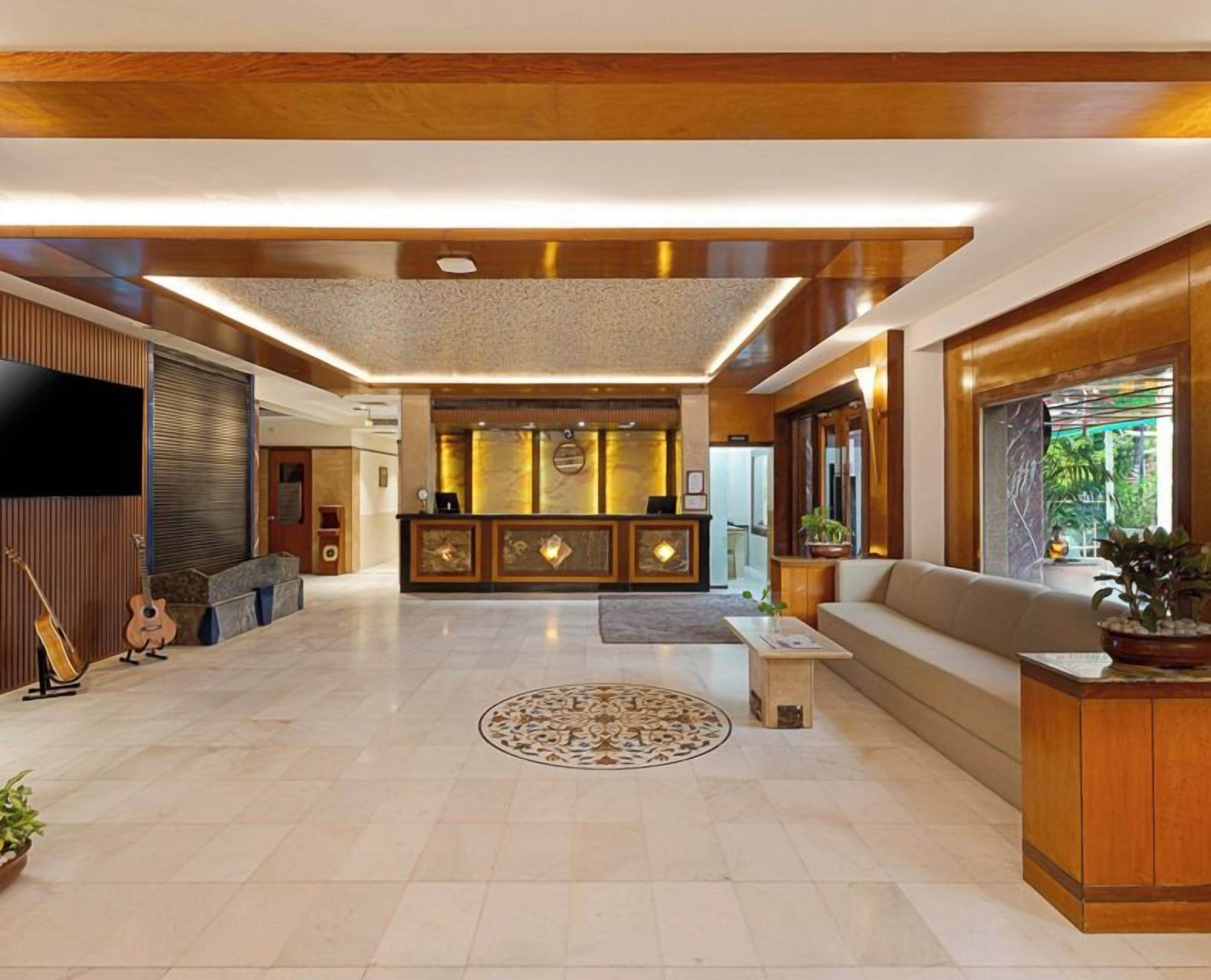 A spacious lobby with a reception desk, sofas, a television, and a patterned rug.