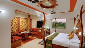 A hotel room with a bed, a sofa, a desk, and a TV. - Hotel Amar (Agra)