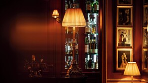 Uma área de bar com uma luminária grande e elaborada, um balcão e uma seleção de garrafas de bebidas.