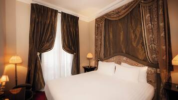 Habitación de hotel con una cama grande, dos lámparas de noche, una mesita de noche y un cabecero con un diseño decorativo.