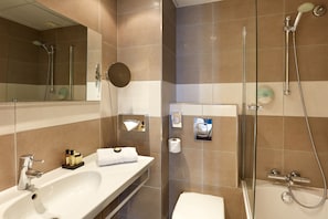 Une salle de bain moderne avec un grand miroir, un lavabo blanc, une douche à parois de verre et des toilettes.