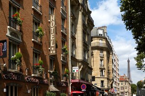 Un hôtel avec une enseigne indiquant « HÔTEL » et une pizzeria avec des enseignes représentant des drapeaux « PIZZA » et « ITALIE ».