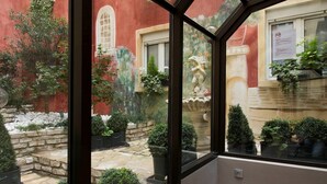 A conservatory with a view of a courtyard, stone flooring, and potted plants.