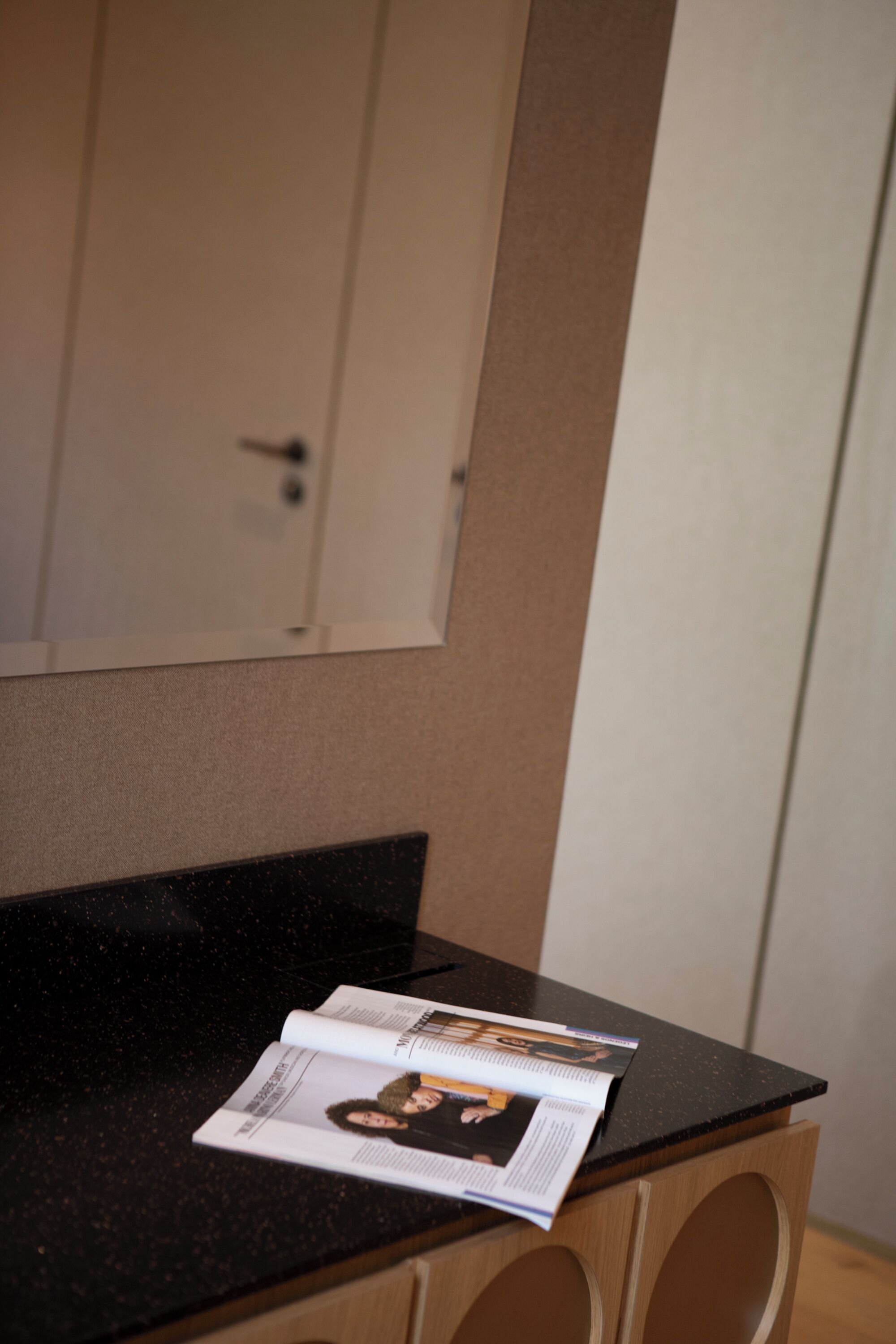 A magazine on a black countertop with a wooden cabinet below.