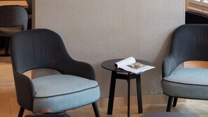 A room with two armchairs, a small table, a green rug, and a handbag on the floor. - Makom Pereire (Paris)