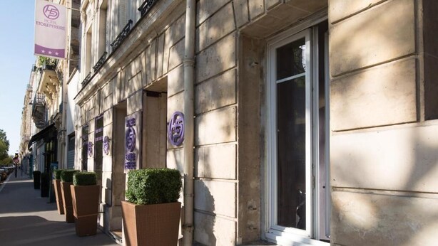 A row of hotel rooms with large windows and a stone facade. - Makom Pereire (Paris)