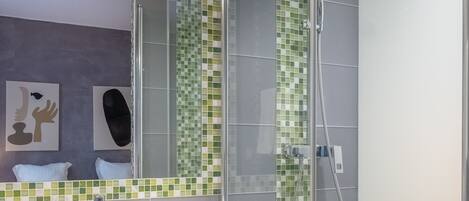 A modern bathroom with a glass-enclosed shower, a white sink, and a mirror above it.