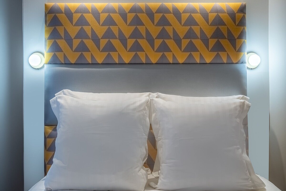 A bed with white pillows and a geometric patterned headboard.