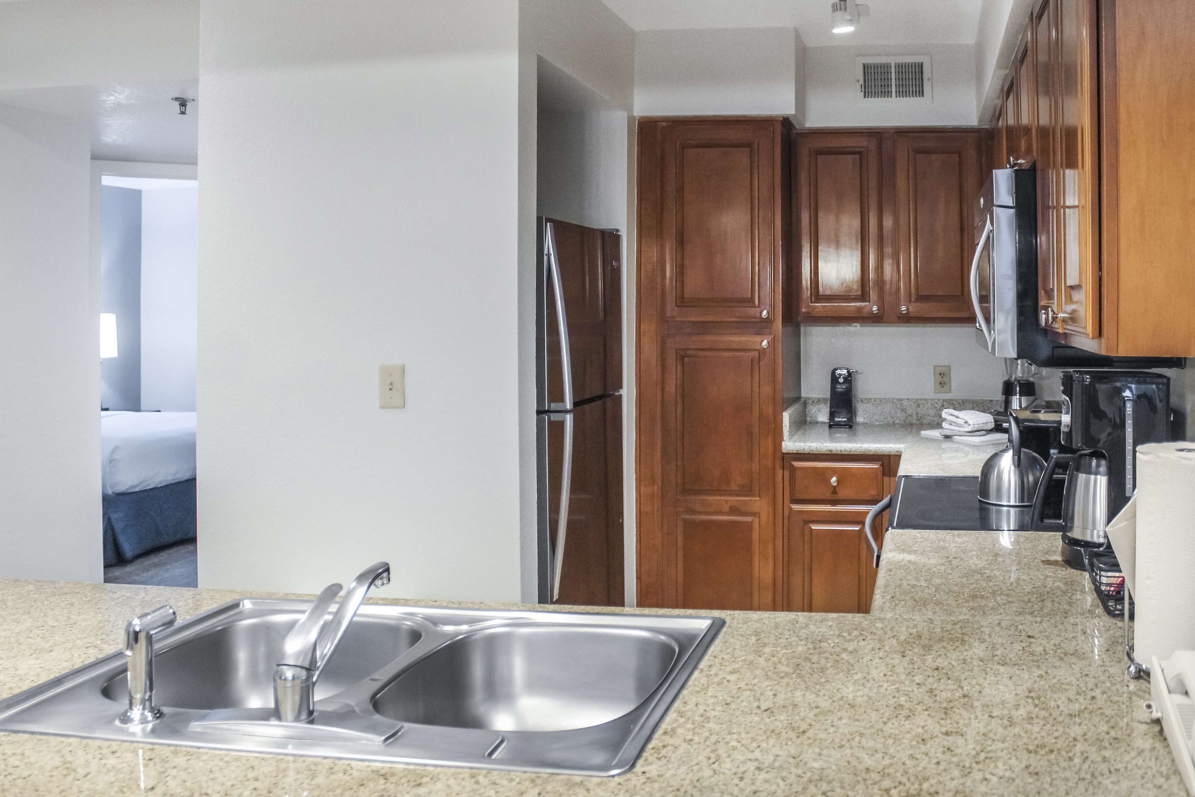 A modern kitchen with granite countertops, stainless steel appliances, and wooden cabinets.