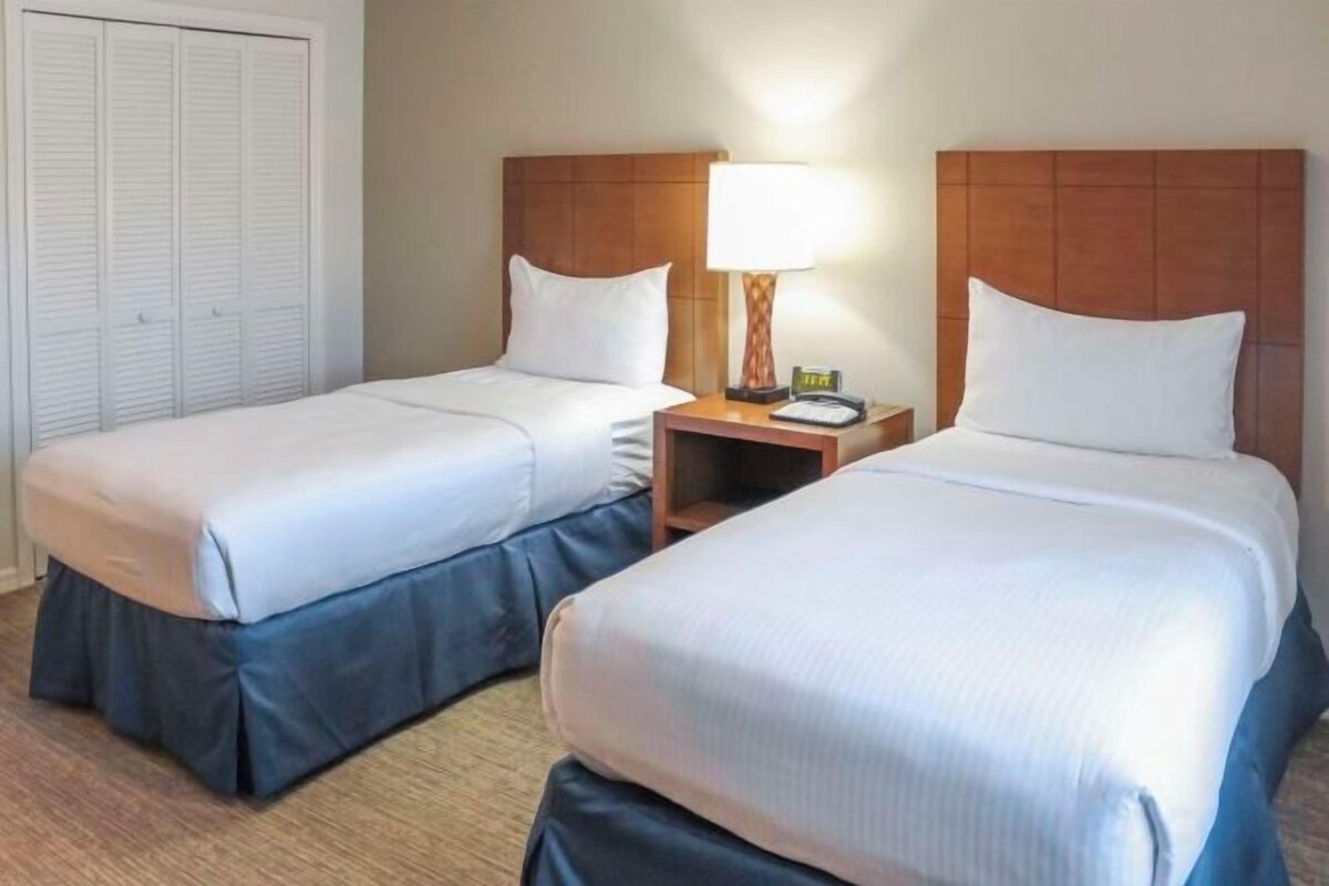 Een hotelkamer met twee bedden, een nachtkastje met een lamp en een kast.