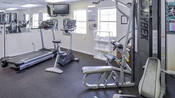 A gym with exercise equipment, a treadmill, and a weight machine.