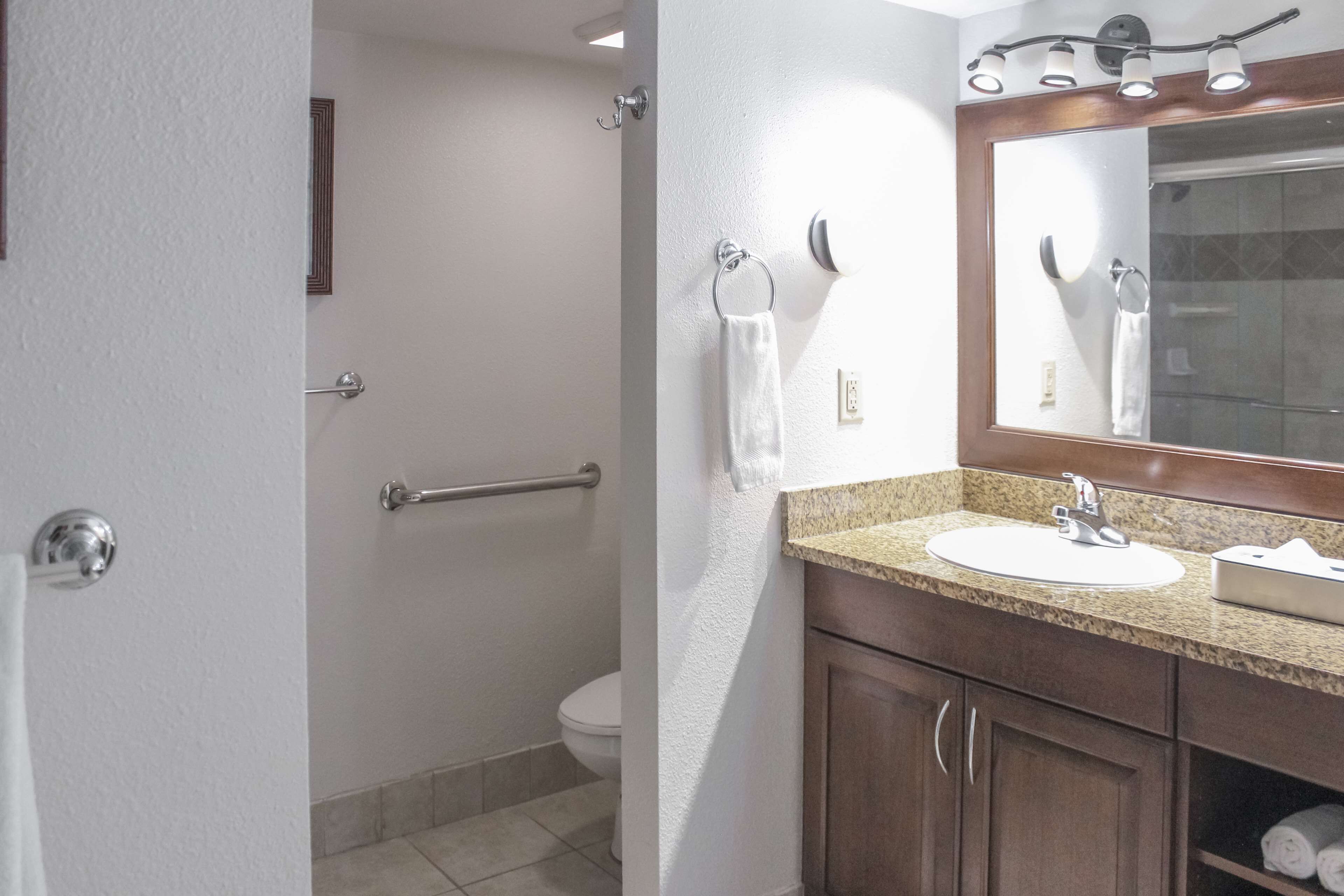 A bathroom with a sink, mirror, towel rack, and a shower area.