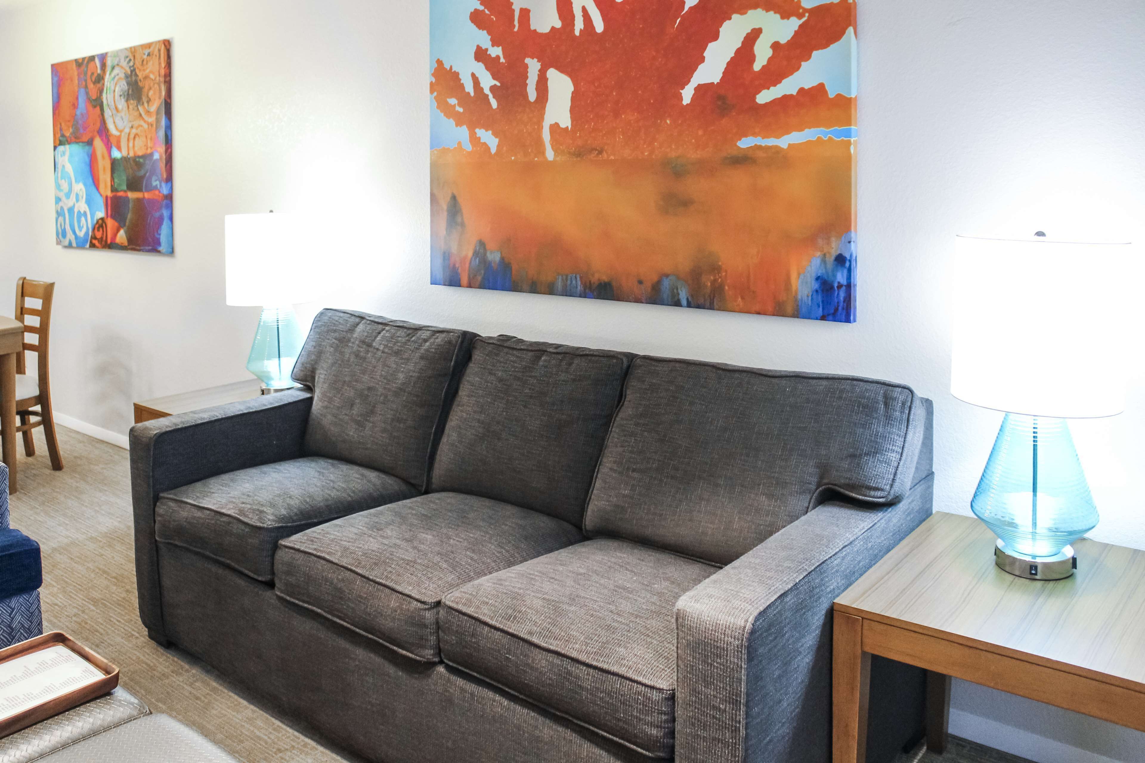 A living room with a gray sofa, a wooden coffee table, and two wall-mounted lamps.