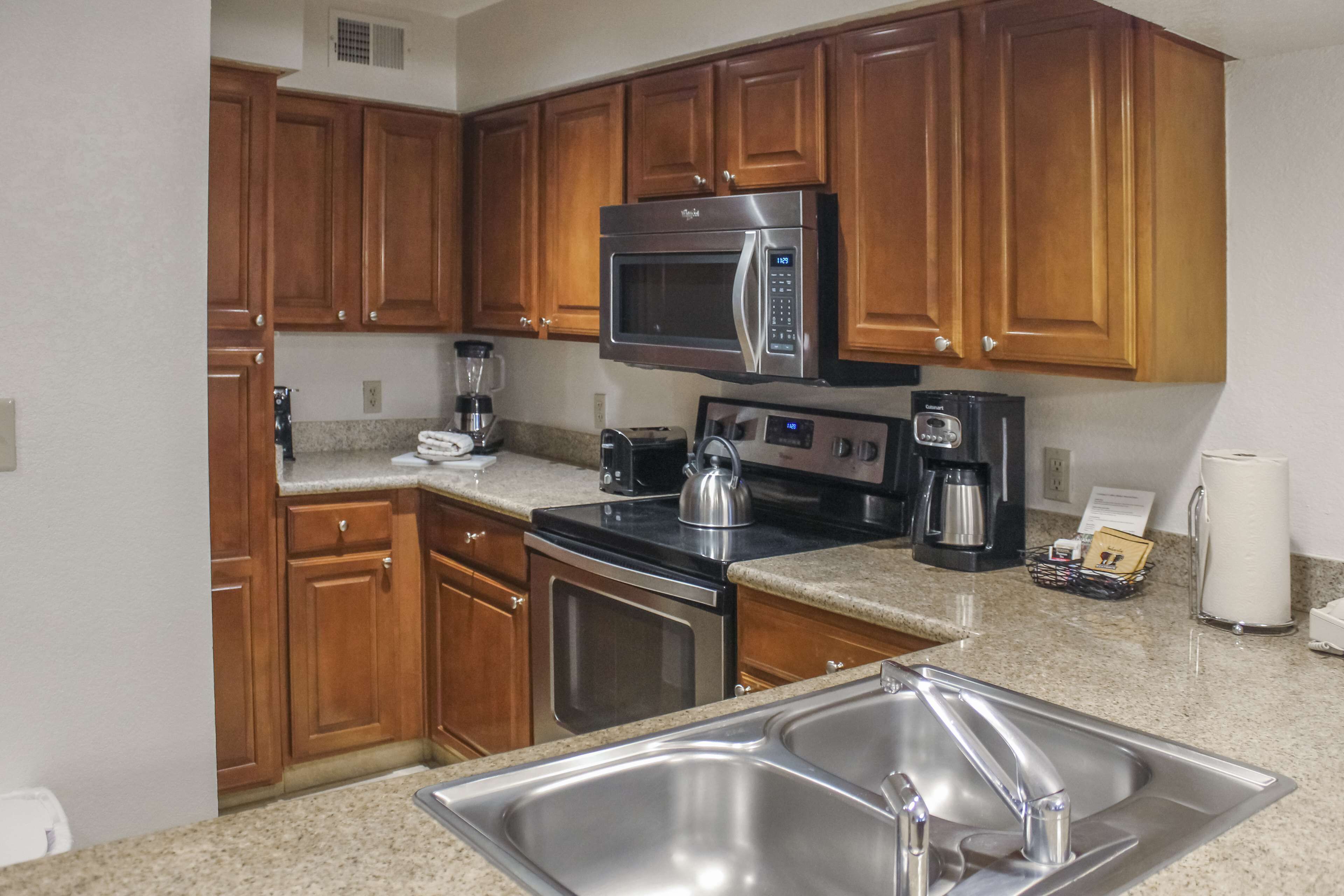 A kitchen with wooden cabinets, stainless steel appliances, a sink, and a countertop.