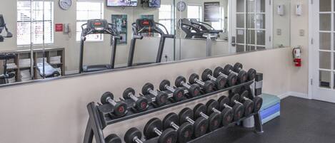 A gym with exercise equipment, a mirror, and a clock.