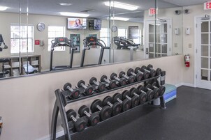 A gym with exercise equipment, a mirror, and a clock.
