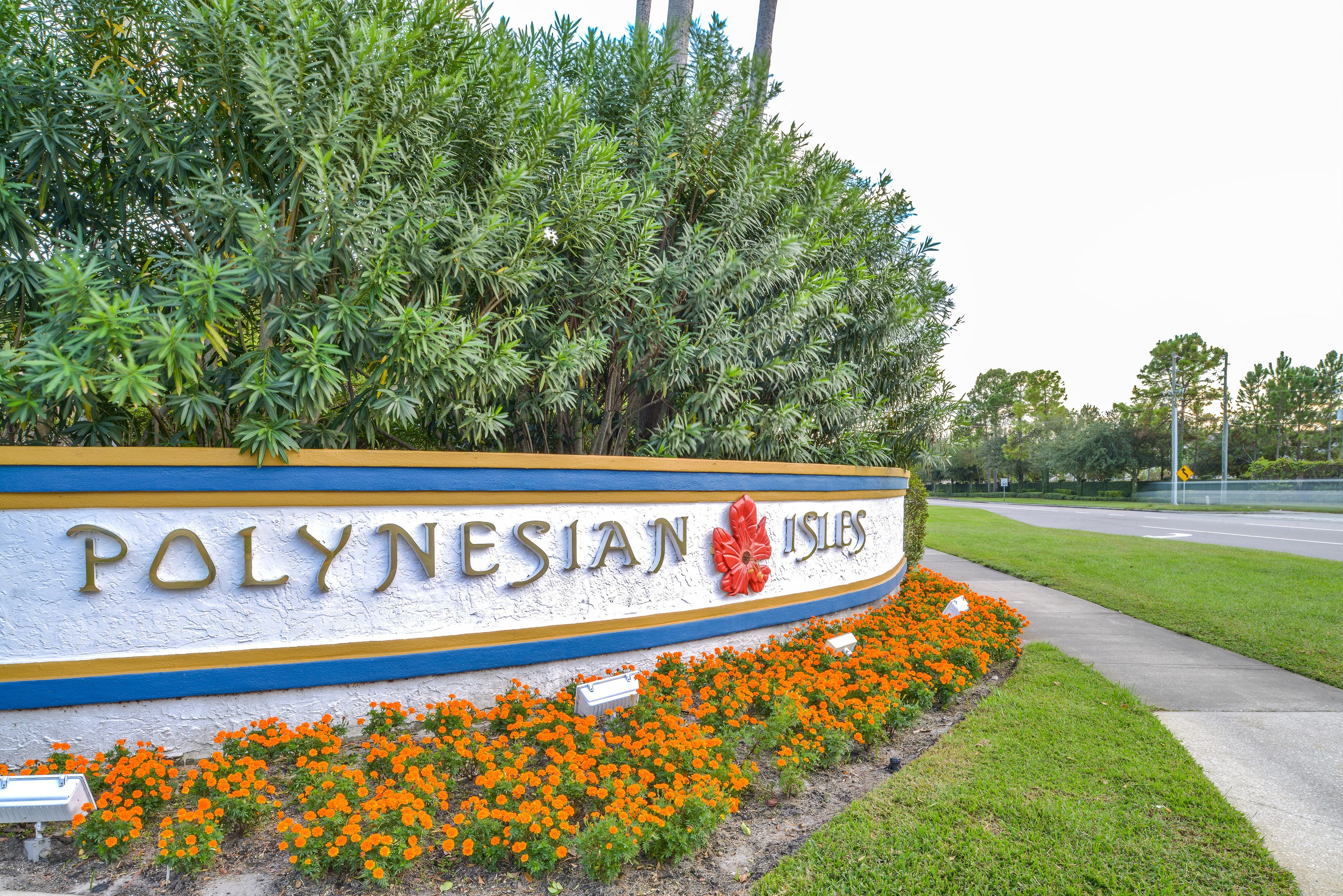 Un panneau indiquant l’entrée de Polynesian Isles, avec un parterre de fleurs devant.