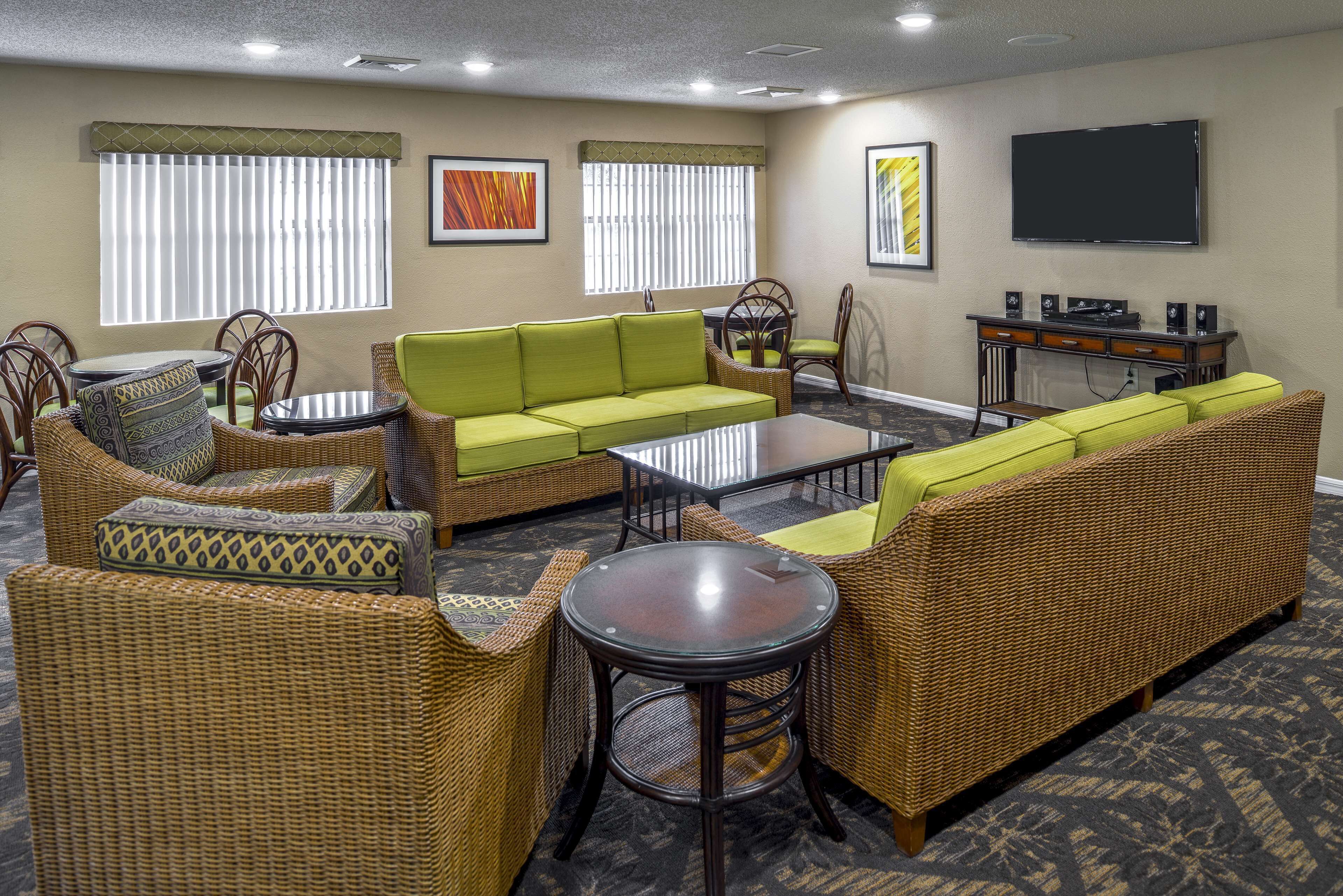 A hotel room with wicker furniture, a flat-screen TV, and artwork on the walls.