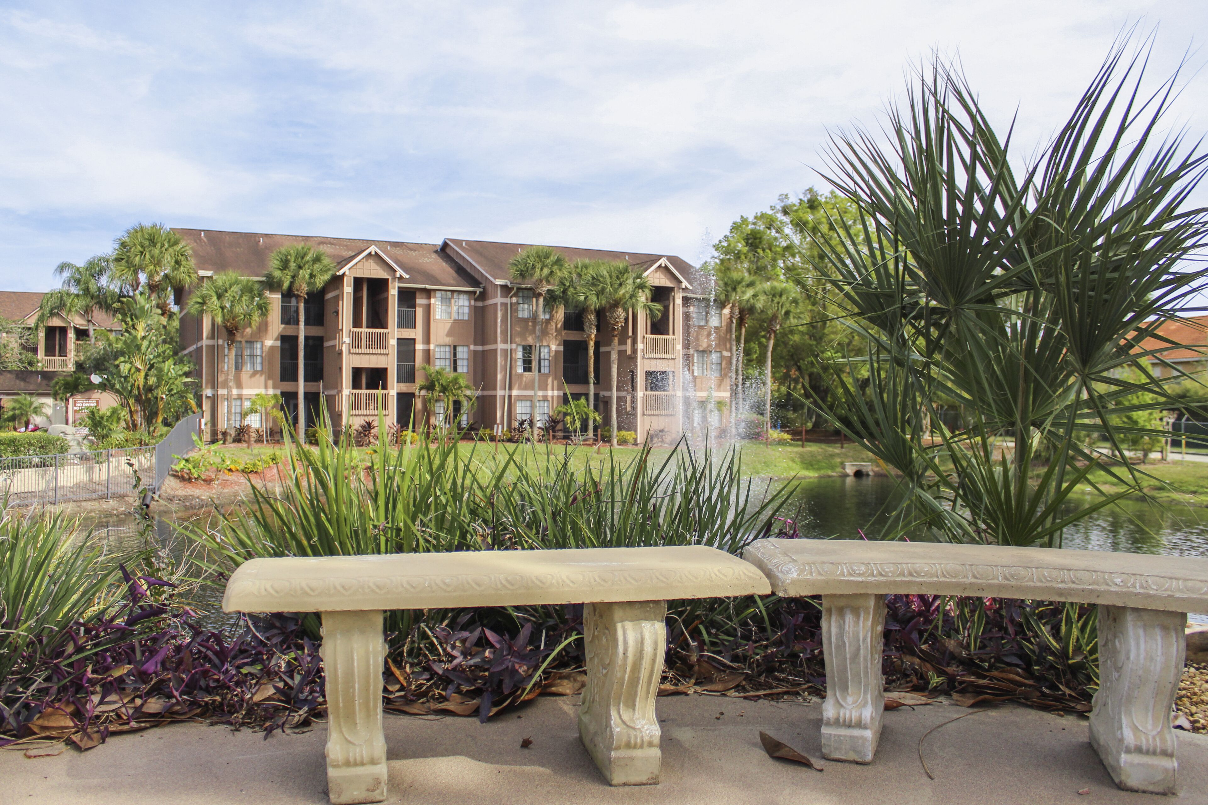 A bench in a landscaped area with a building in the background.