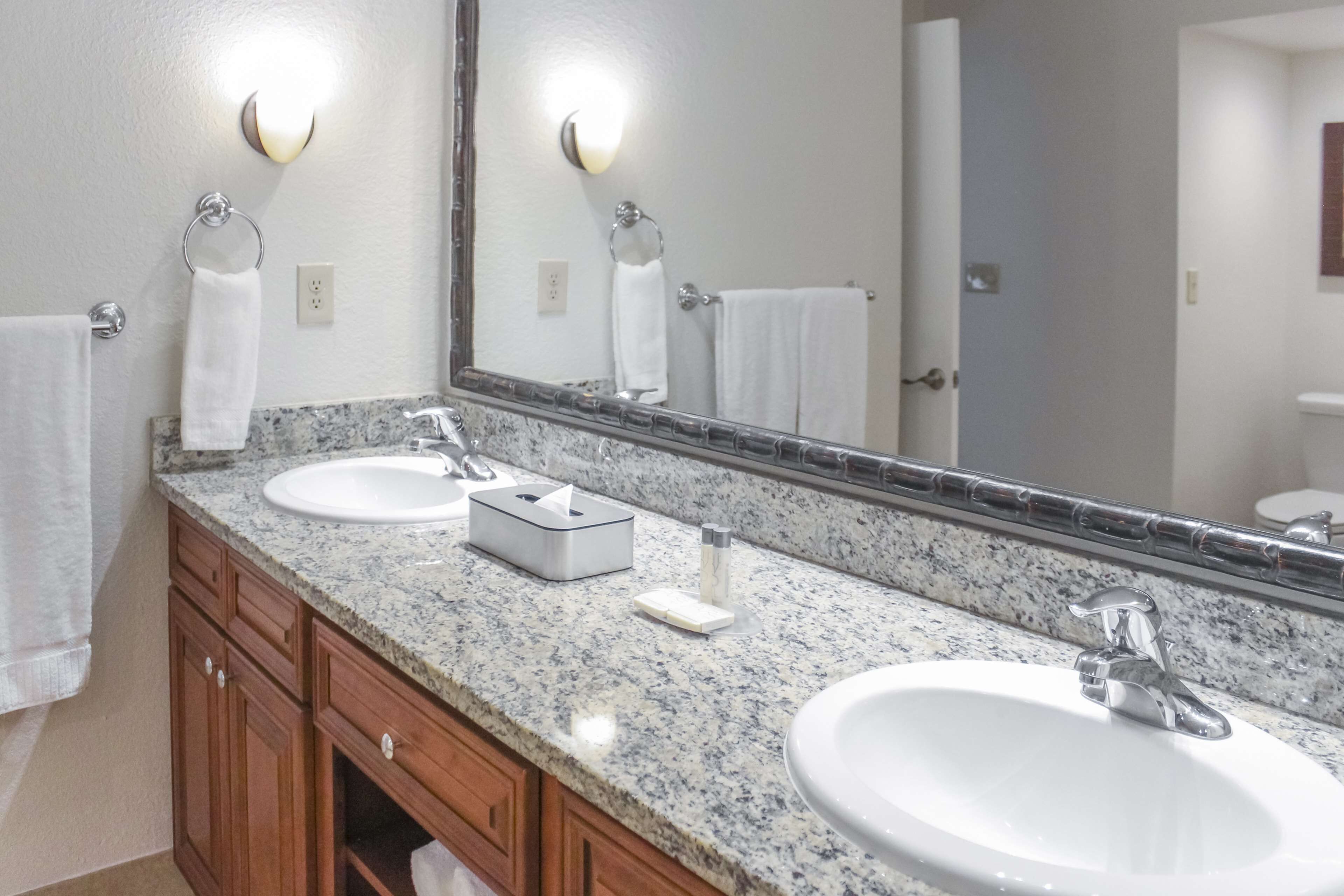 A bathroom with two sinks, a large mirror, and wooden cabinets.