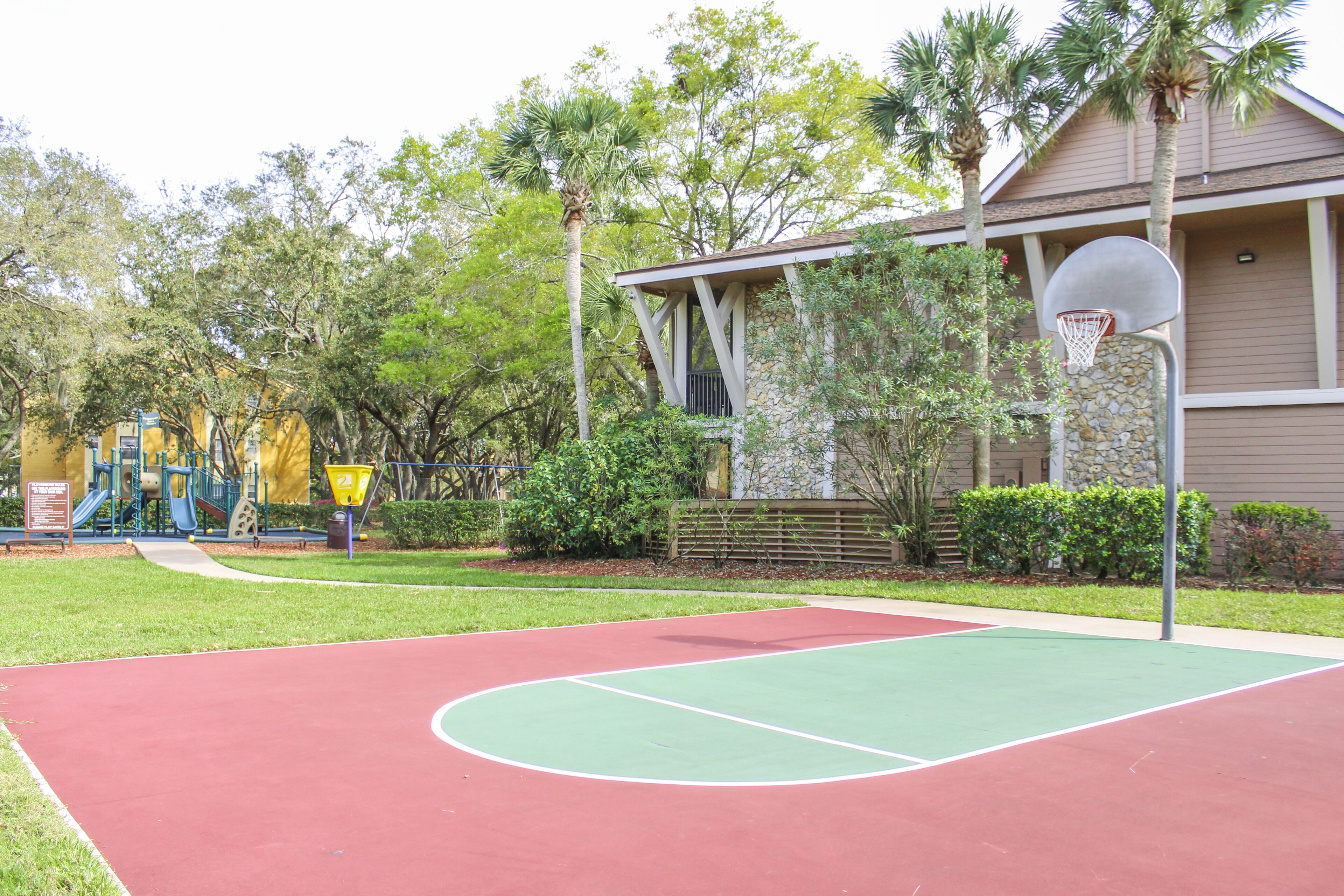 Ein Basketballplatz im Freien mit einem Spielplatz im Hintergrund.