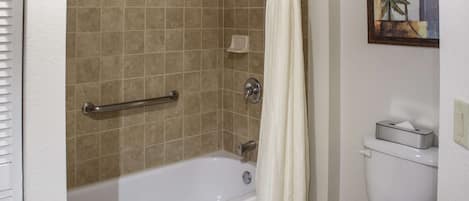 A bathroom with a bathtub, toilet, and a shower curtain.