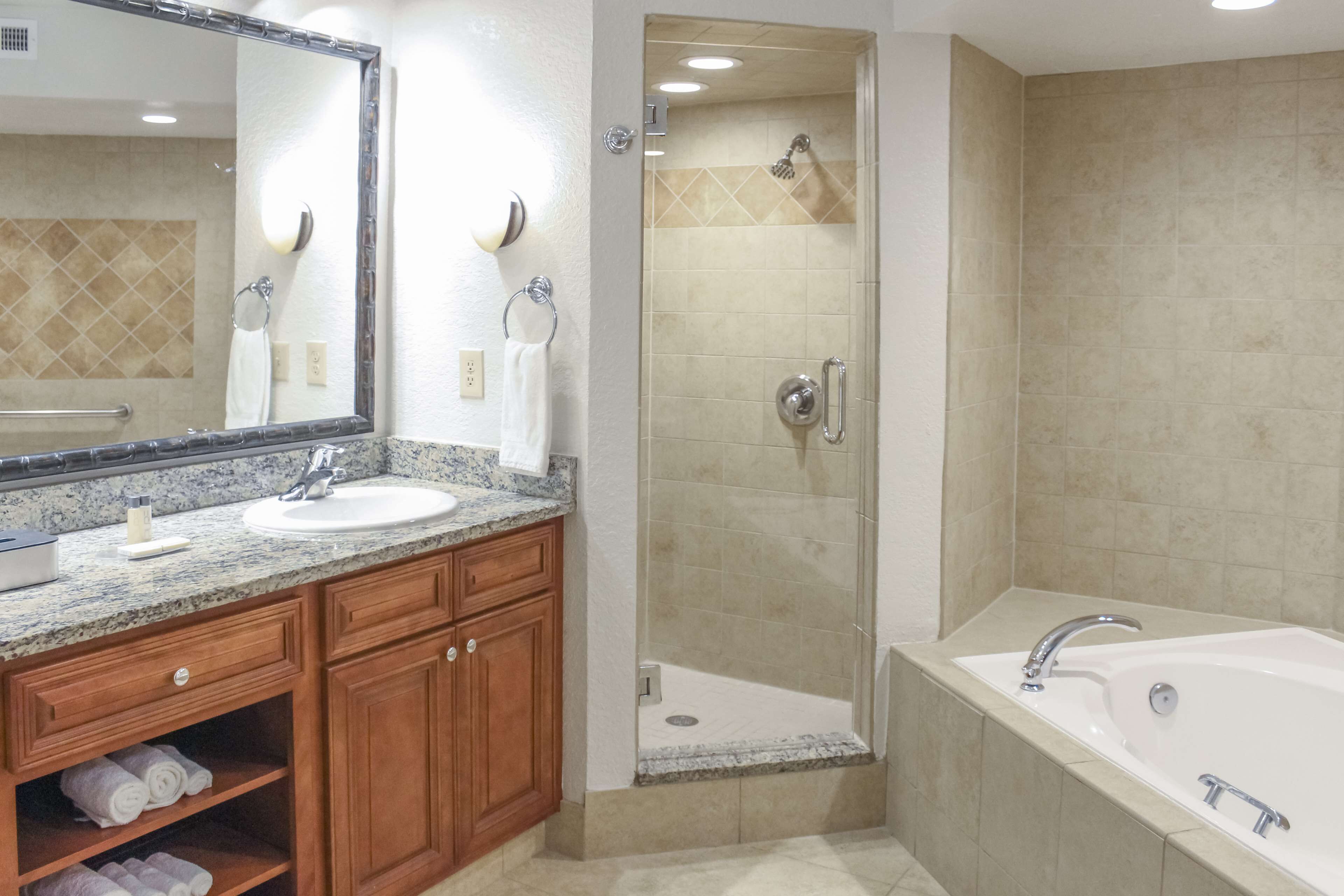 A modern bathroom with a large mirror, two sinks, a shower enclosure, and a bathtub.