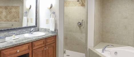A modern bathroom with a large mirror, two sinks, a shower enclosure, and a bathtub.