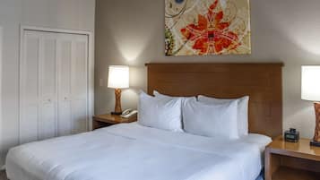 Habitación de hotel con una cama grande, una mesita de noche con lámpara, teléfono y un adorno en la pared.