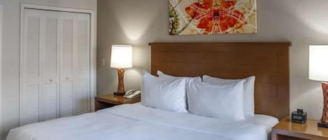 A hotel room with a large bed, a nightstand with a lamp, a phone, and a decorative wall piece.