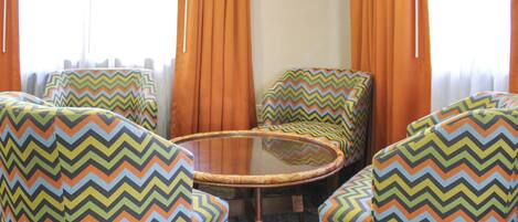 Una habitación con una mesa redonda de vidrio rodeada por cuatro sillas con tapicería de estampado en zigzag.