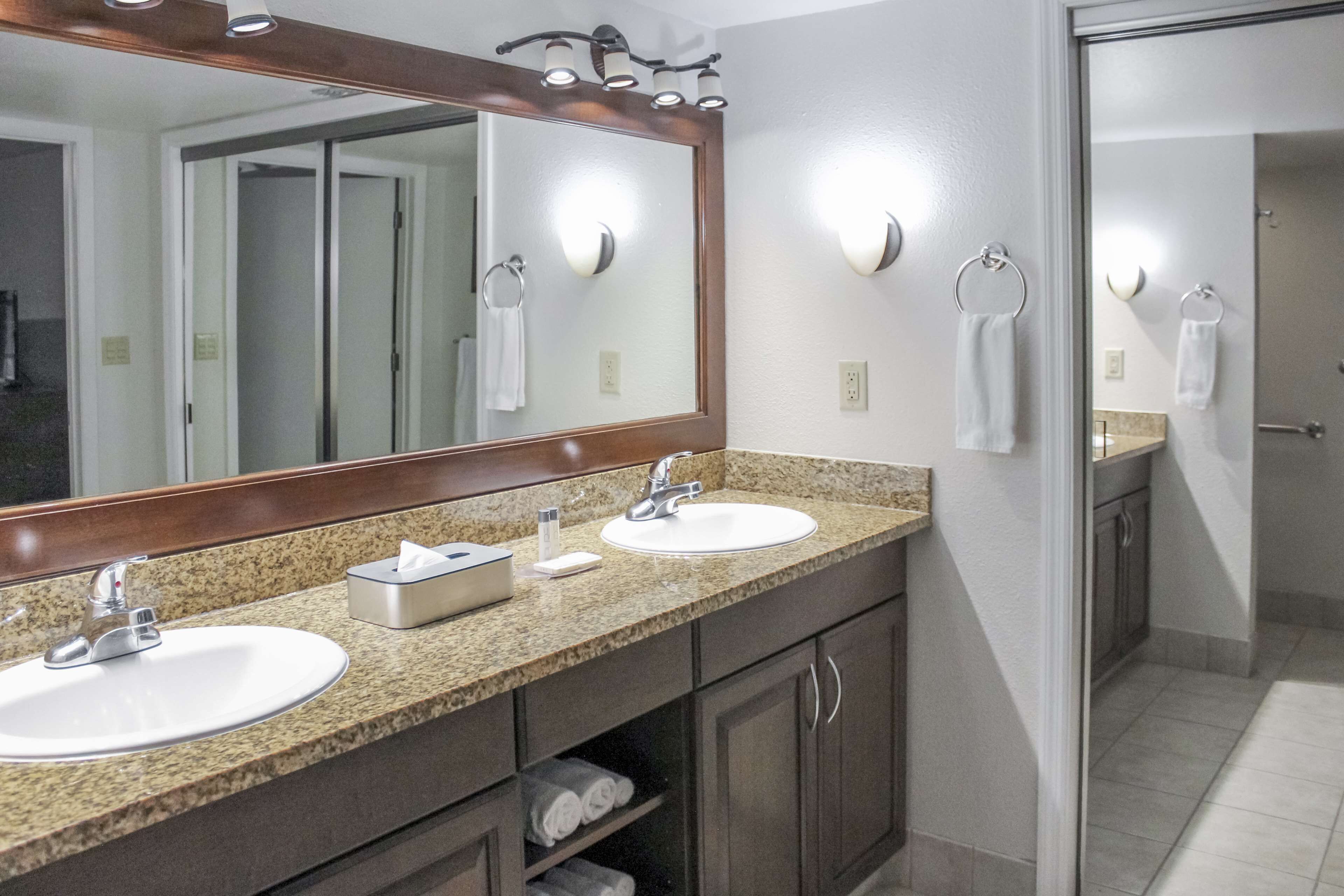 Une salle de bain avec deux lavabos, un grand miroir et un porte-serviettes.